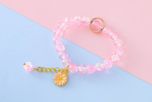 Close-up of pink cracked glass bead bracelet with gold daisy pendant for girls