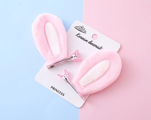 Close-up of pink plush bunny ear hair clips with white velvet lining on display card