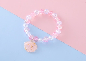 Detail of pink beaded bracelet featuring iridescent beads and a golden glitter shell charm