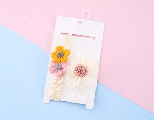 Detail von cremefarbenen Baby-Stirnbändern mit Strickblumen und Champagner-Netzbögen