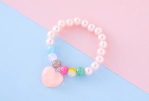 Détail d'un bracelet de perles roses pour filles avec pendentif coeur et perles colorées