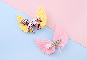 Détail de barrettes licorne à paillettes roses avec ailes scintillantes et clips canard
