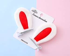 Detail of plush white rabbit ear hair clips with red inner ear on a display card