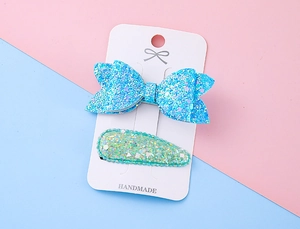 Gros plan d'un nœud papillon bleu scintillant et d'épingles à cheveux sur carte