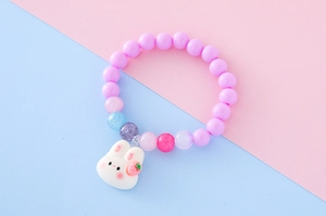 Détail du bracelet à perles avec perles violettes et pendentif lapin blanc sur fond pastel