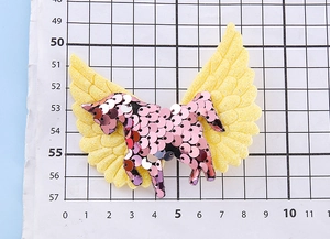 Détail d'une barrette licorne scintillante avec paillettes violettes et ailes jaunes