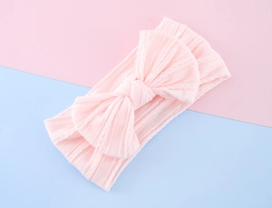 Close-up of baby pink cable knit headband with a soft elastic bow for infants