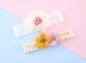 Detailansicht von zwei Baby-Stirnbändern aus Spitze mit zarten Stoffblumen in Pastellfarben