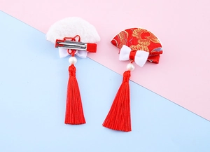 Detail of red fan-shaped hair clips with golden embroidery and long silk tassels