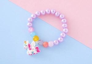 Gros plan d'un bracelet en perles pour enfants avec un joli pendentif licorne