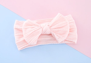 Detail view of the soft pale pink knitted baby headband with a large decorative bow