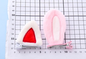 Detailed view of plush cat and rabbit ear hair clips on a scale measuring mat