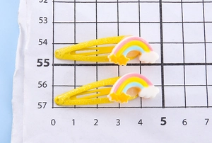 Dettaglio di due graziose clip per capelli unicorno su scala che mostra 5 cm di lunghezza