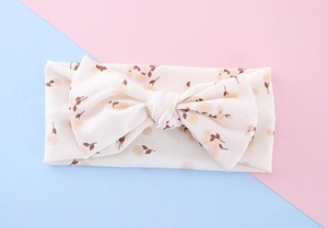 Detailed close-up of a floral bow headband made of textured ribbed cotton for infants