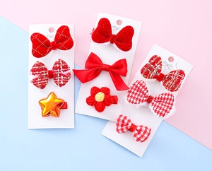 Detailed close-up of festive red children hair clips with bowknot and plaid fabric textures