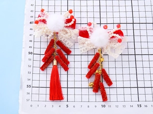 Détail de pinces à cheveux à nœud rouge avec pompons blancs, franges et clochettes