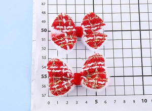 Detaillierte Nahaufnahme roter und weißer Tweed-Schleifen-Clips mit Goldfaden und Pelz