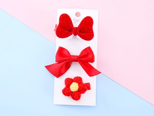 Three-piece set of red plush and satin bow hair clips for kids on a card
