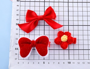 Detailed close-up of a 3-piece set featuring red bow hair clips and crochet flower accessories
