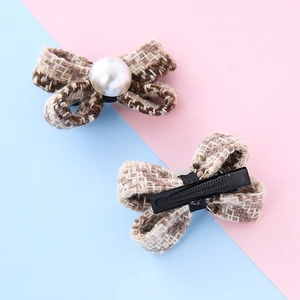 Fermagli per capelli a fiocco in tweed marrone con perle bianche su sfondo rosa e blu