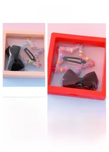 Détails de barrettes étoile en laine et nœuds en velours dans un coffret cadeau carré