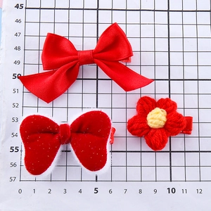 Three-piece set of red festive hair clips including plush velvet bows and woven flower