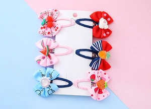 Detailed set of 6 children bow hair clips with cartoon fruit charms on pink and blue background