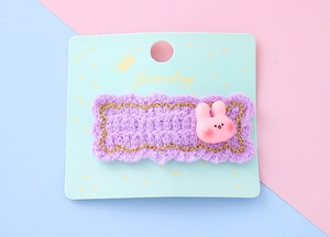 Détail de la barrette en tricot violet avec bordure dorée et petit lapin rose mignon