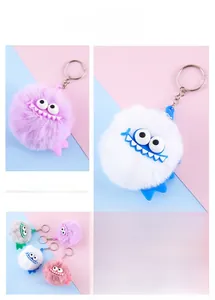 Detailed view of colorful monster pompom keychains in white, purple, pink and grey fur