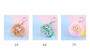 Detailed close-up of fluffy monster plush keychains in brown, grey and pink colors