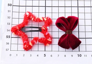 Détail montrant la taille de la pince étoile rouge et du nœud en velours sur papier