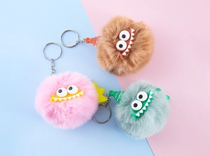 Close-up of fluffy faux rabbit fur monster keychains in pink, brown and teal colors