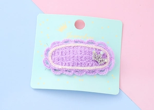 Détail d'une pince à cheveux violette crochetée avec couronne en strass sur sa carte