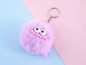 Close-up of purple faux rabbit fur monster keychain with big eyes and a wide toothy grin