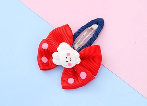 Close-up of a red polka dot ribbon bow hair clip with a cute resin cartoon charm for girls
