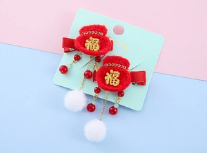 Detail of red knitted koi lucky bag hair clips with tassels and plush pom-poms for girls