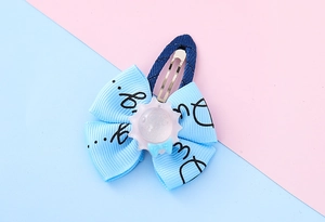 Close-up of cute children's blue ribbon bow hair clip with denim fabric wrap and gear decor