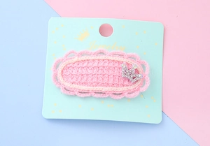 Détail d'une barrette couronne en laine rose tricotée avec strass sur carte support
