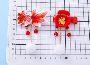 Detail of Chinese New Year hair clips with embroidered koi fish and red lucky fortune bag