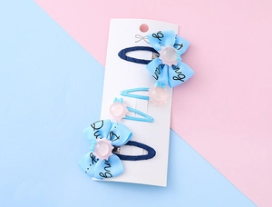 Dettaglio di 4 fermagli per capelli con fiocco blu per bambini su carta con sfondo rosa