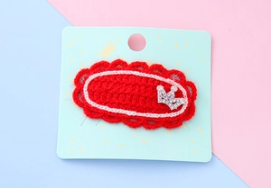 Détail d'une pince à cheveux rouge au crochet avec couronne argentée et strass