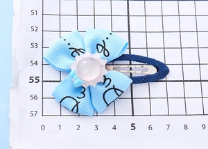 Detailed close-up of a blue ribbon flower hair clip with a sun resin core on a grid