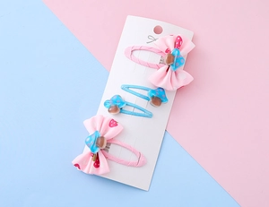 Dettaglio di fermagli per capelli con fiocco rosa e funghi glitterati blu su carta
