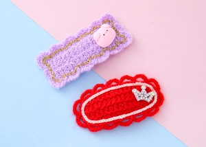 Gros plan de barrettes à cheveux tricotées avec petit cochon rose et couronne sur fond bicolore