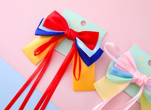 Detail of layered satin bow hair clips with long ribbons on jewelry display card
