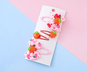 Dettaglio di fermagli per capelli a fragola con fiocchi rosa e clip glitterate rosse