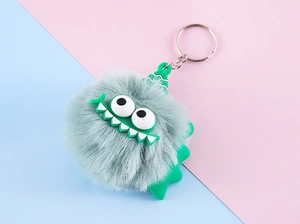 Close-up of fluffy grey monster plush keychain with green horns and metal ring