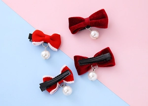 Dettaglio di fermagli per capelli a fiocco in velluto rosso con perle e clip a becco d'anatra