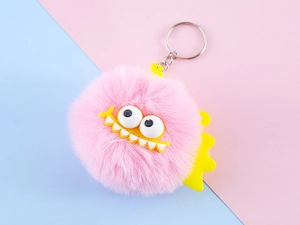 Close-up of pink fluffy monster keychain with big eyes and silver metal keyring