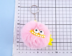Close-up of a pink plush monster keychain with white eyes and yellow teeth detail